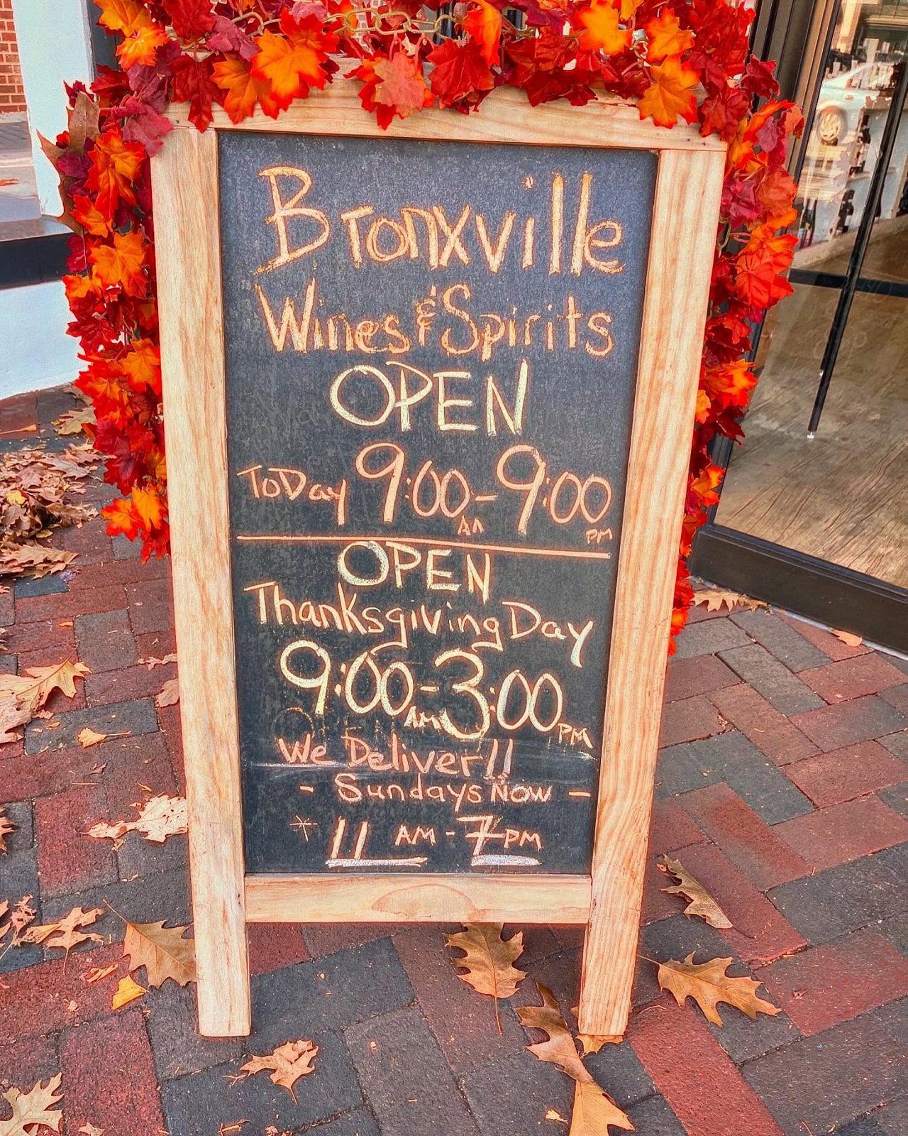 Sidewalk chalkboard sign reading Bronxville Wines & Spirits, We Deliver